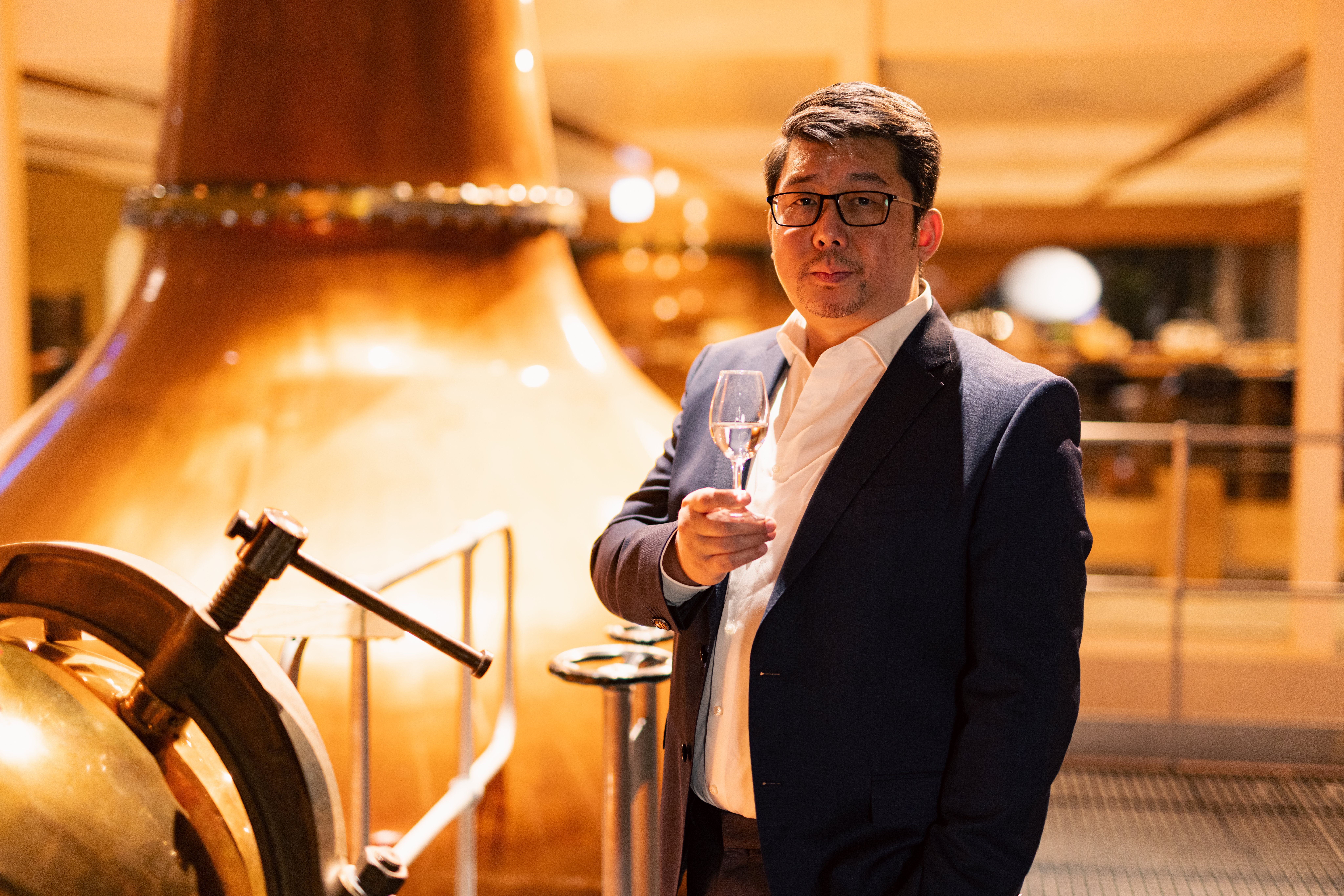Ian Chang stands in front of the distillery's two copper pot stills 