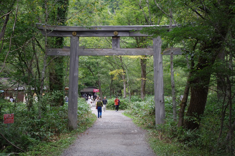 a hiker walks through a large wooden torii gate